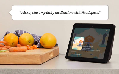  An Echo Show on a desk. At upper part of the picture is a dialog box containing texts reading as “Alexa, start my daily meditation with Headspace.”  
